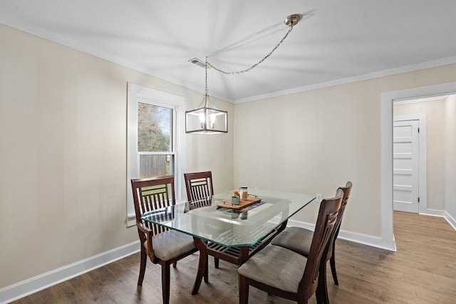 dining room with wood-type flooring, an inviting chandelier, and crown molding