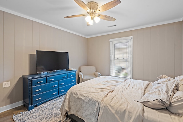 bedroom featuring ceiling fan, dark hardwood / wood-style flooring, crown molding, and wooden walls