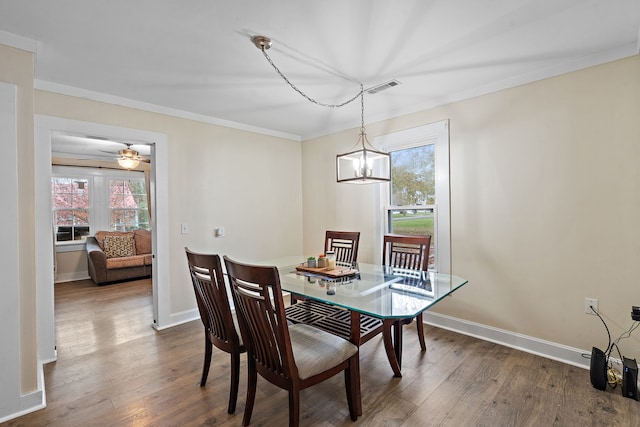 dining room with ceiling fan with notable chandelier, crown molding, and dark wood-type flooring