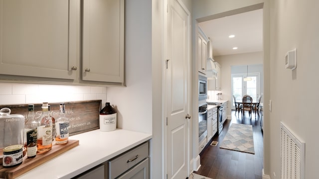 kitchen featuring decorative backsplash, appliances with stainless steel finishes, dark hardwood / wood-style flooring, and gray cabinetry