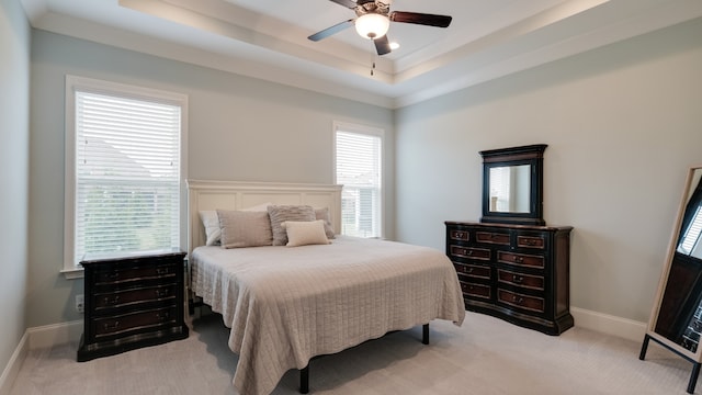 bedroom with ceiling fan, light carpet, and a tray ceiling