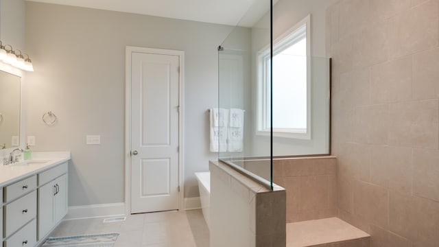 bathroom with tile patterned floors, vanity, a healthy amount of sunlight, and tiled shower