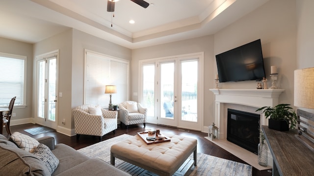 living room with dark hardwood / wood-style floors, a healthy amount of sunlight, a raised ceiling, and ceiling fan