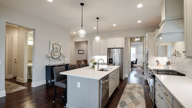 kitchen featuring pendant lighting, white cabinets, sink, an island with sink, and dark hardwood / wood-style flooring