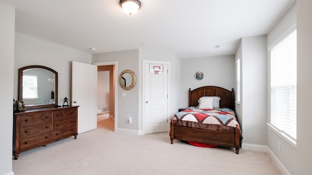 bedroom featuring connected bathroom and light carpet