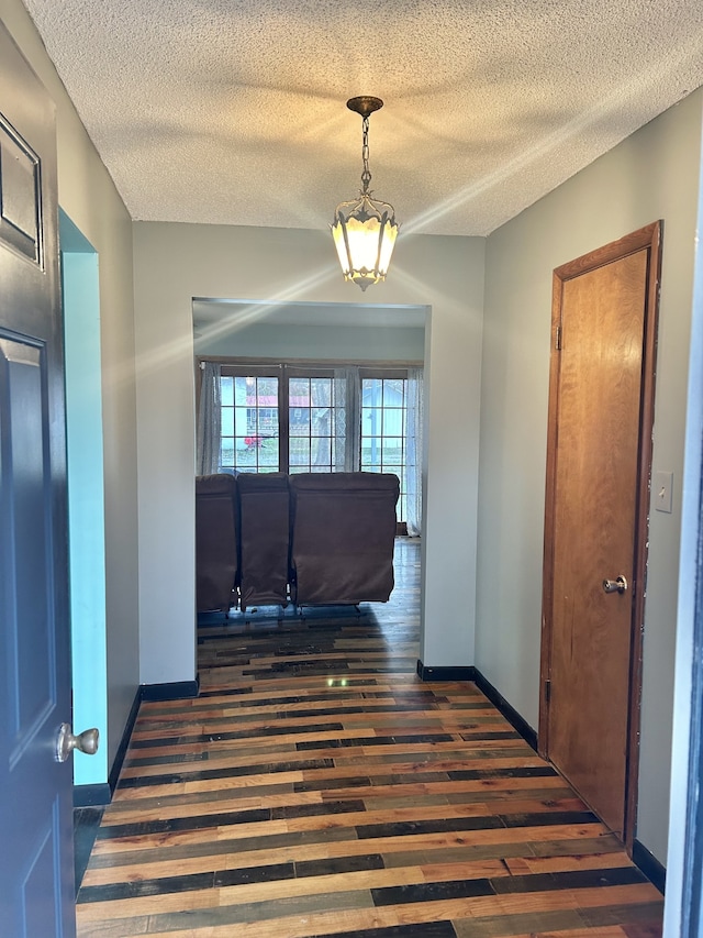 hall with a textured ceiling and dark hardwood / wood-style floors