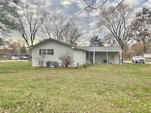 rear view of property with central air condition unit and a lawn