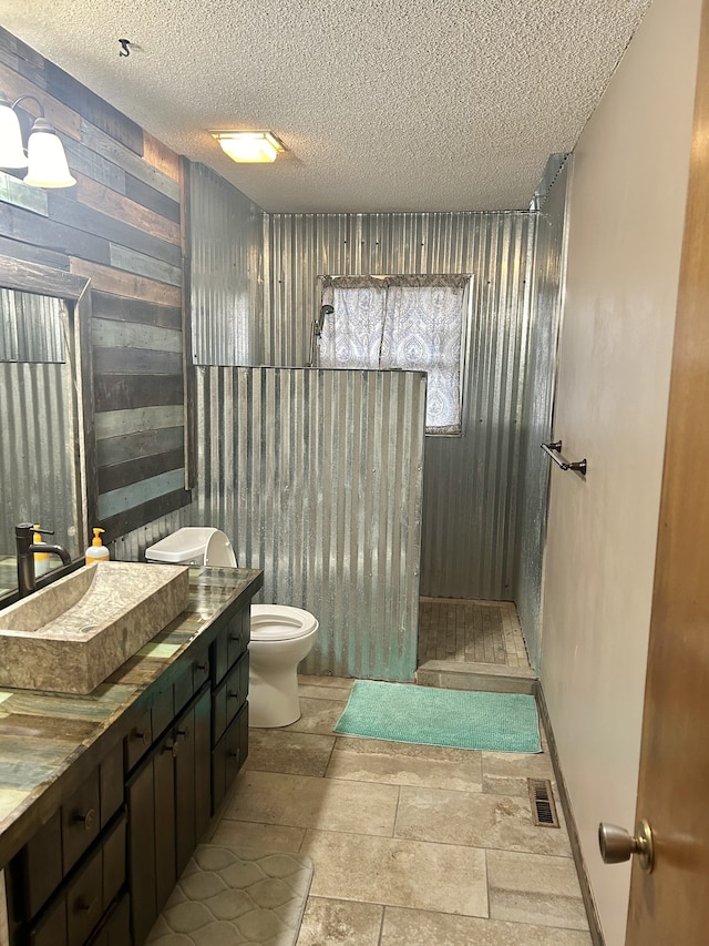 bathroom with walk in shower, vanity, a textured ceiling, and toilet