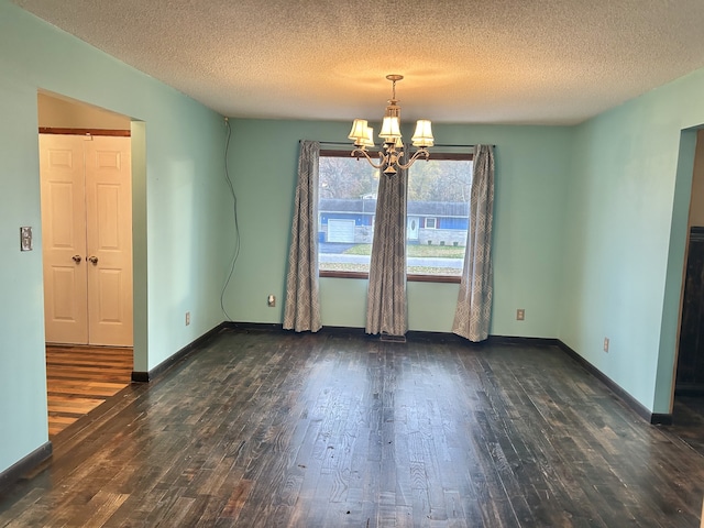 unfurnished room with a textured ceiling, dark hardwood / wood-style flooring, and an inviting chandelier