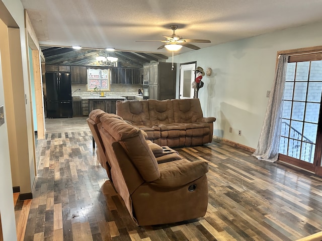 living room featuring ceiling fan with notable chandelier, sink, wooden walls, dark hardwood / wood-style floors, and a textured ceiling