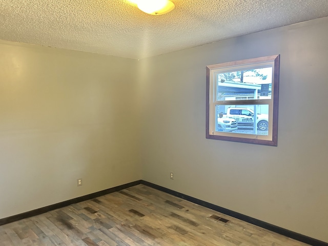 unfurnished room with wood-type flooring and a textured ceiling