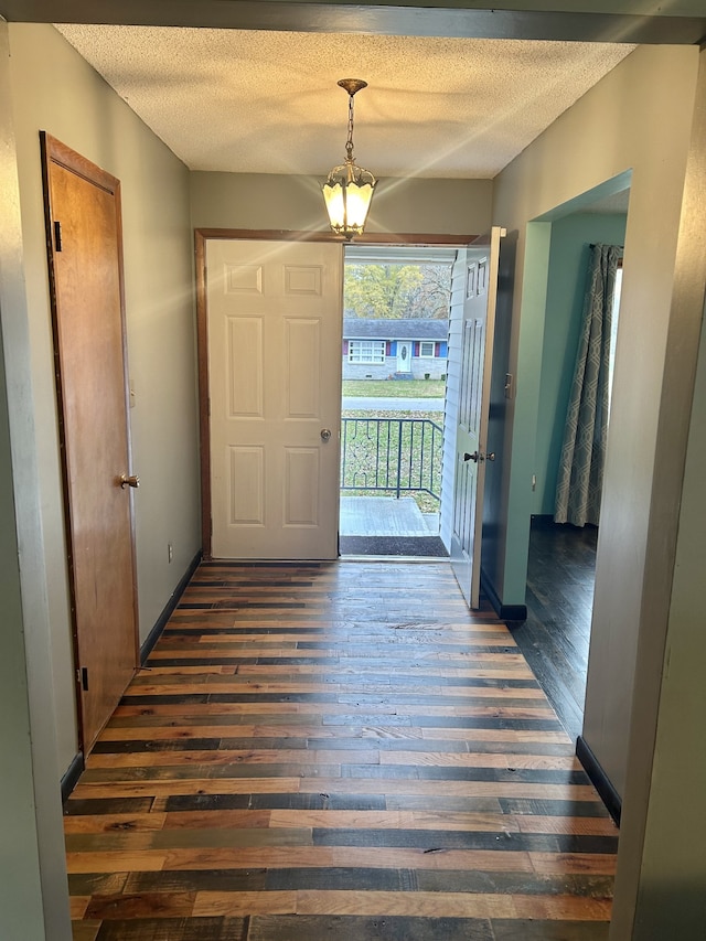 foyer featuring dark hardwood / wood-style floors, a textured ceiling, and an inviting chandelier