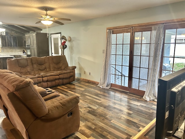 living room featuring a textured ceiling, ceiling fan, and dark wood-type flooring