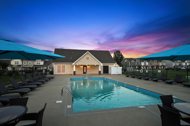 pool at dusk with a patio area