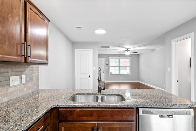 kitchen with light stone countertops, backsplash, ceiling fan, sink, and dishwasher