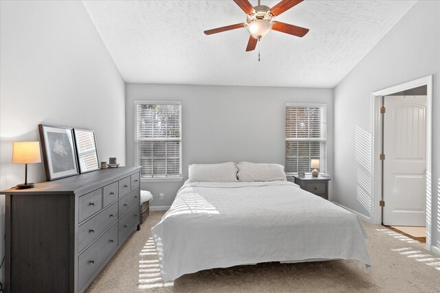 carpeted bedroom featuring ceiling fan, lofted ceiling, and a textured ceiling