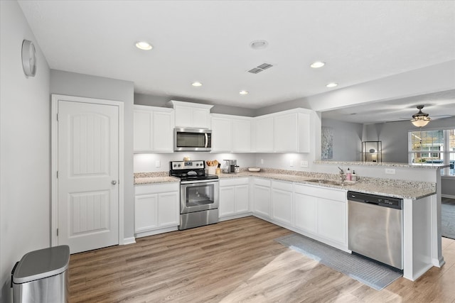 kitchen featuring ceiling fan, stainless steel appliances, white cabinetry, and light hardwood / wood-style flooring