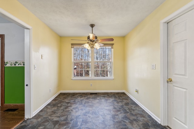 unfurnished dining area with ceiling fan and a textured ceiling