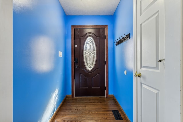 doorway to outside with dark hardwood / wood-style flooring and a textured ceiling