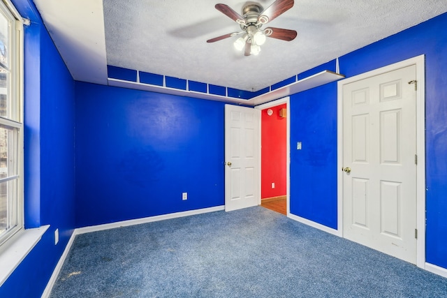 interior space featuring carpet flooring, a textured ceiling, and ceiling fan