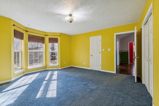 carpeted empty room featuring a textured ceiling