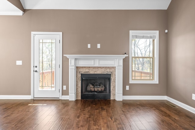 unfurnished living room with a healthy amount of sunlight, dark hardwood / wood-style flooring, and a tile fireplace