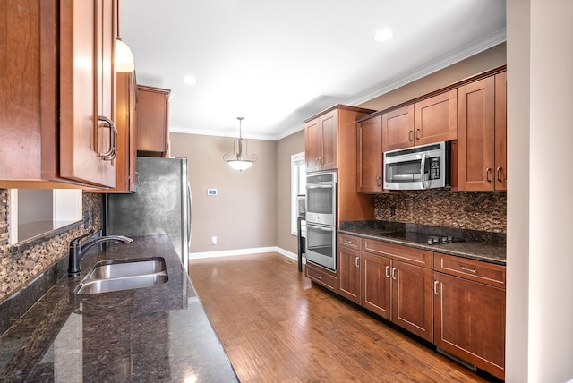 kitchen featuring sink, hanging light fixtures, dark stone countertops, hardwood / wood-style floors, and appliances with stainless steel finishes