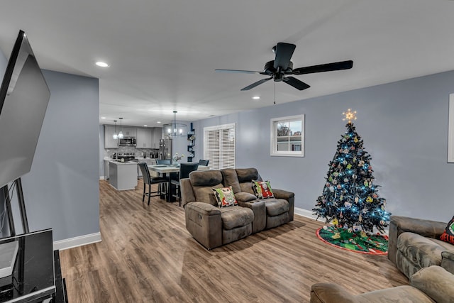 living room featuring ceiling fan with notable chandelier and wood-type flooring