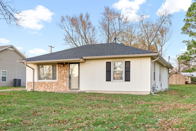 view of front of house featuring cooling unit, a shed, and a front lawn