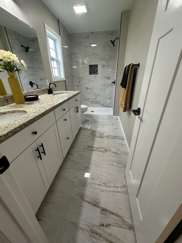 bathroom with vanity, toilet, and a tile shower