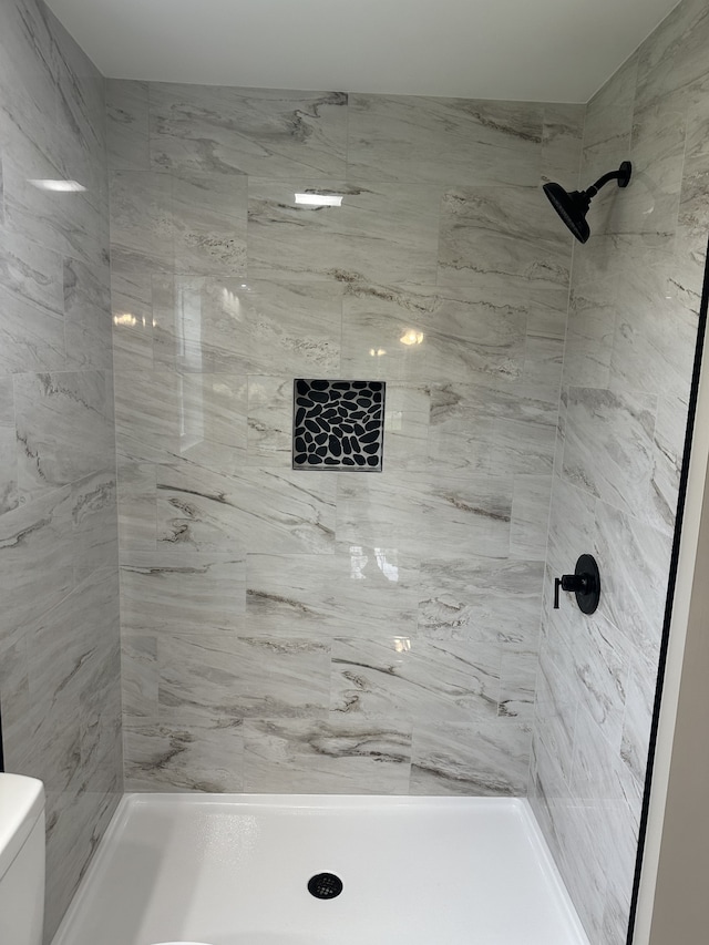 bathroom with toilet and tiled shower