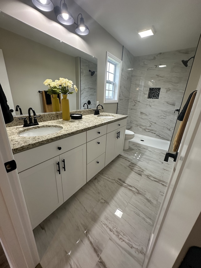 bathroom with vanity, toilet, and tiled shower