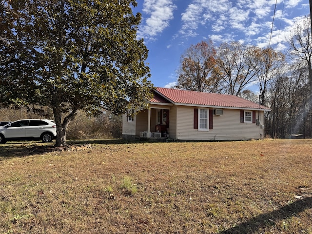 ranch-style home with covered porch, a wall unit AC, and a front lawn