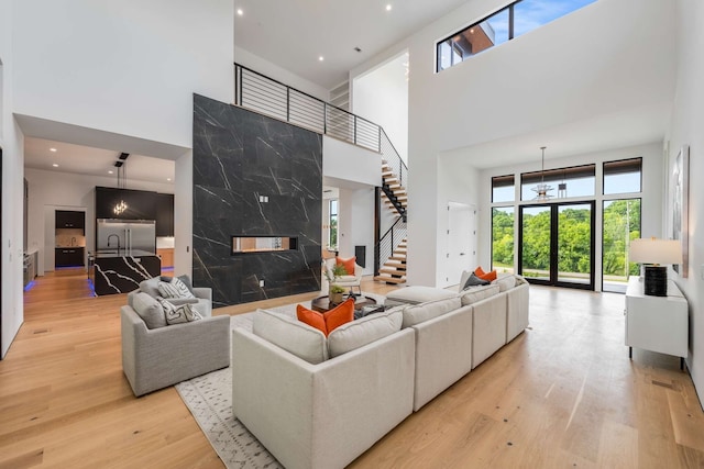 living room featuring a high ceiling, an inviting chandelier, light hardwood / wood-style flooring, and a healthy amount of sunlight