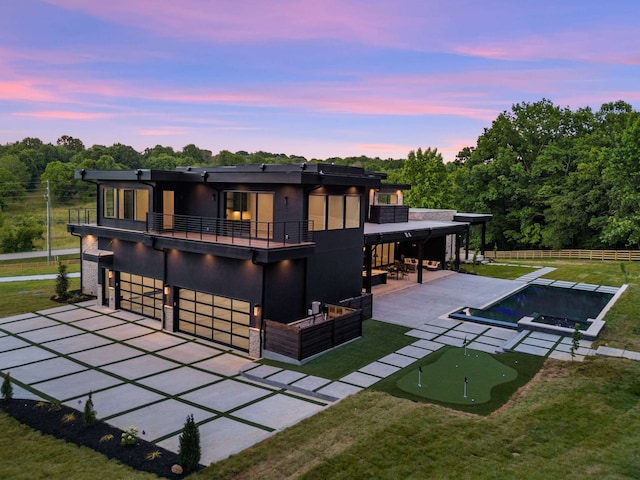 back house at dusk with a patio and a balcony