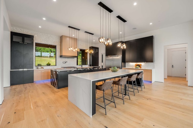 kitchen featuring a center island, light hardwood / wood-style flooring, stainless steel built in refrigerator, pendant lighting, and light brown cabinetry