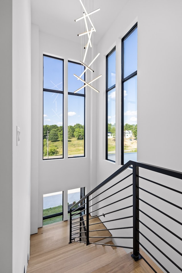 stairway with hardwood / wood-style flooring, plenty of natural light, and a notable chandelier