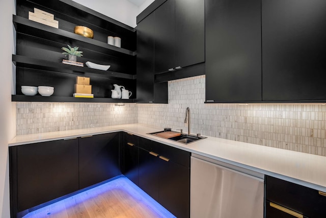 kitchen with backsplash, light hardwood / wood-style flooring, stainless steel dishwasher, and sink