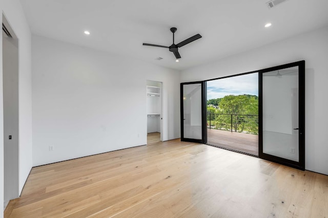 unfurnished bedroom with a walk in closet, a closet, and light wood-type flooring