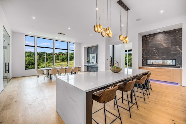 kitchen with a healthy amount of sunlight, light hardwood / wood-style flooring, a center island, and hanging light fixtures