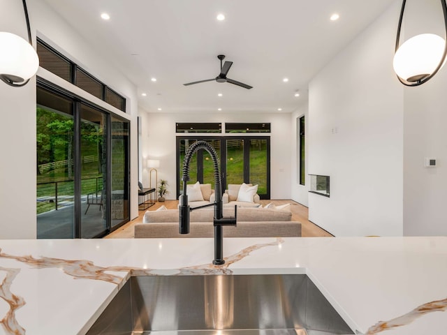 kitchen featuring light stone countertops, ceiling fan, sink, and pendant lighting