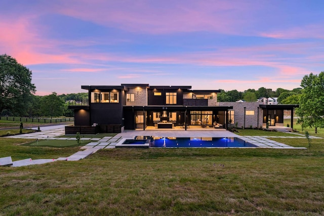 back house at dusk featuring a yard and a patio area