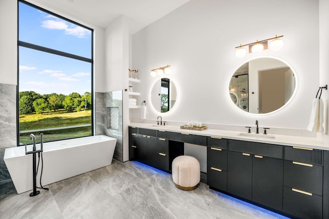 bathroom featuring a bath, vanity, and a healthy amount of sunlight