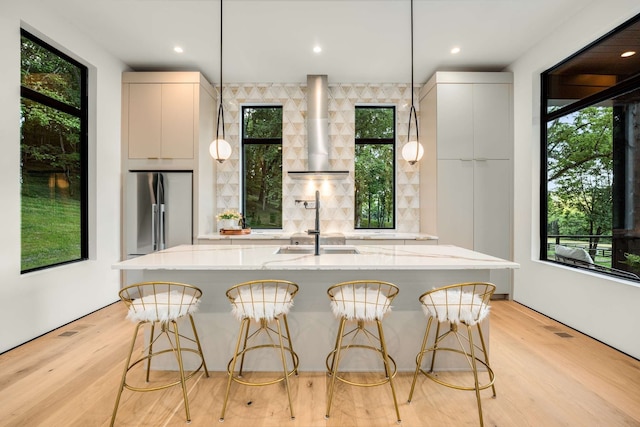 kitchen with a breakfast bar, stainless steel fridge, light wood-type flooring, and sink