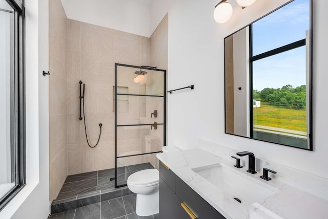 bathroom featuring tile patterned floors, vanity, toilet, and tiled shower