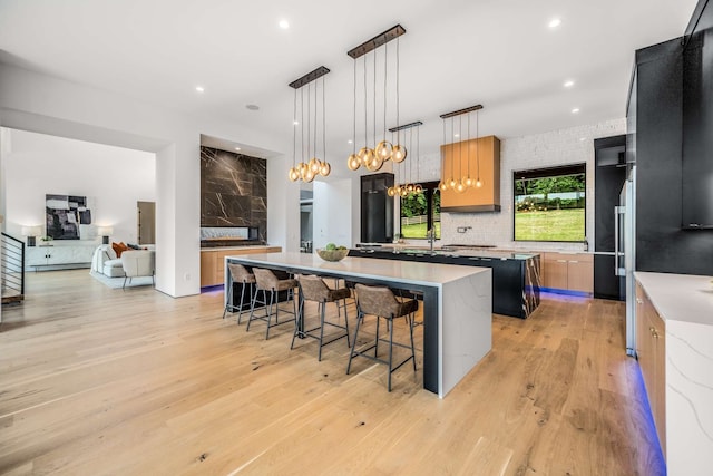 kitchen featuring backsplash, light hardwood / wood-style floors, decorative light fixtures, a breakfast bar, and a kitchen island