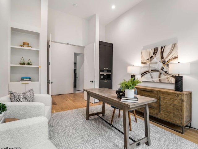 office featuring high vaulted ceiling and light hardwood / wood-style floors