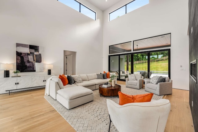 living room with hardwood / wood-style flooring, plenty of natural light, a high ceiling, and a baseboard heating unit