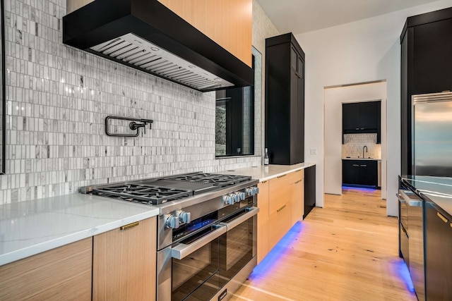 kitchen with light wood-type flooring, light stone counters, custom exhaust hood, light brown cabinets, and high quality appliances