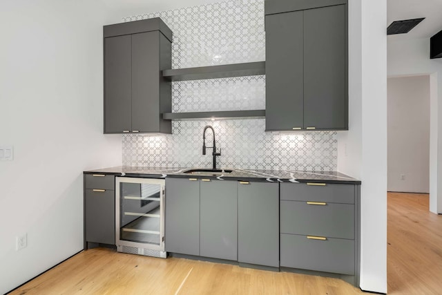 kitchen with wine cooler, sink, gray cabinets, and light wood-type flooring